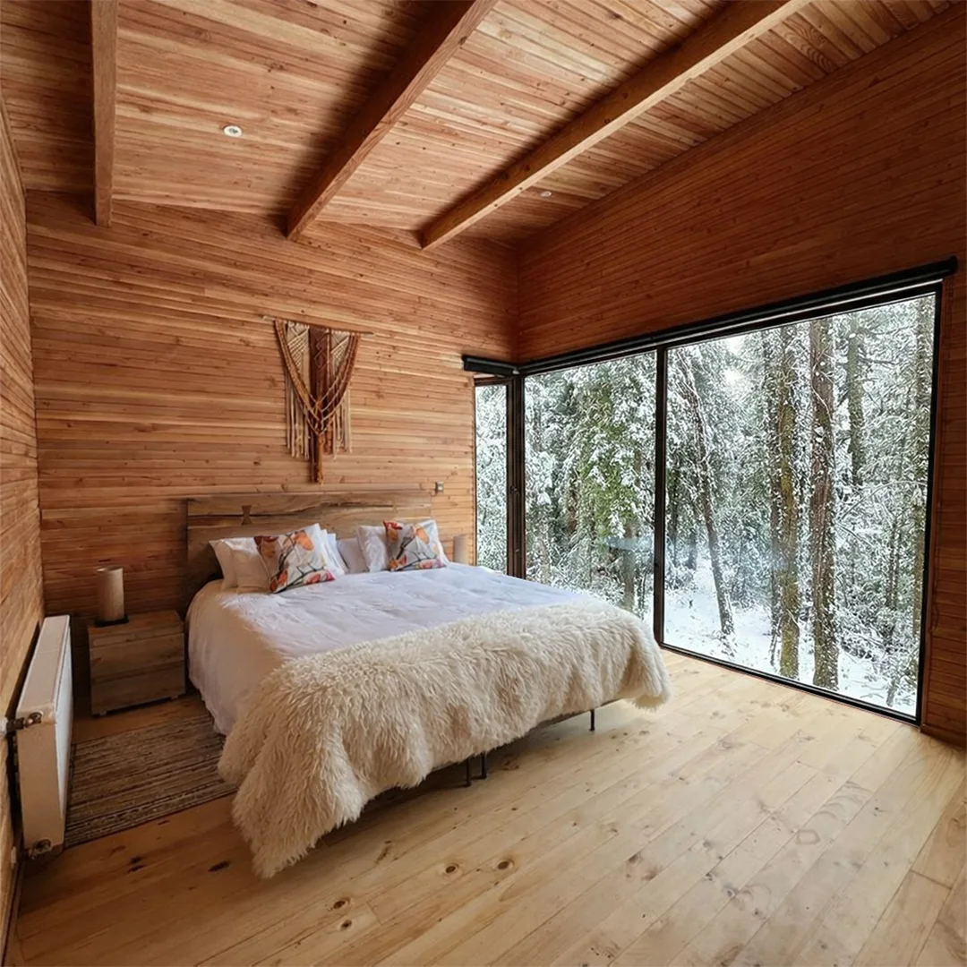 Habitación principal con el bosque nevado tras el ventanal